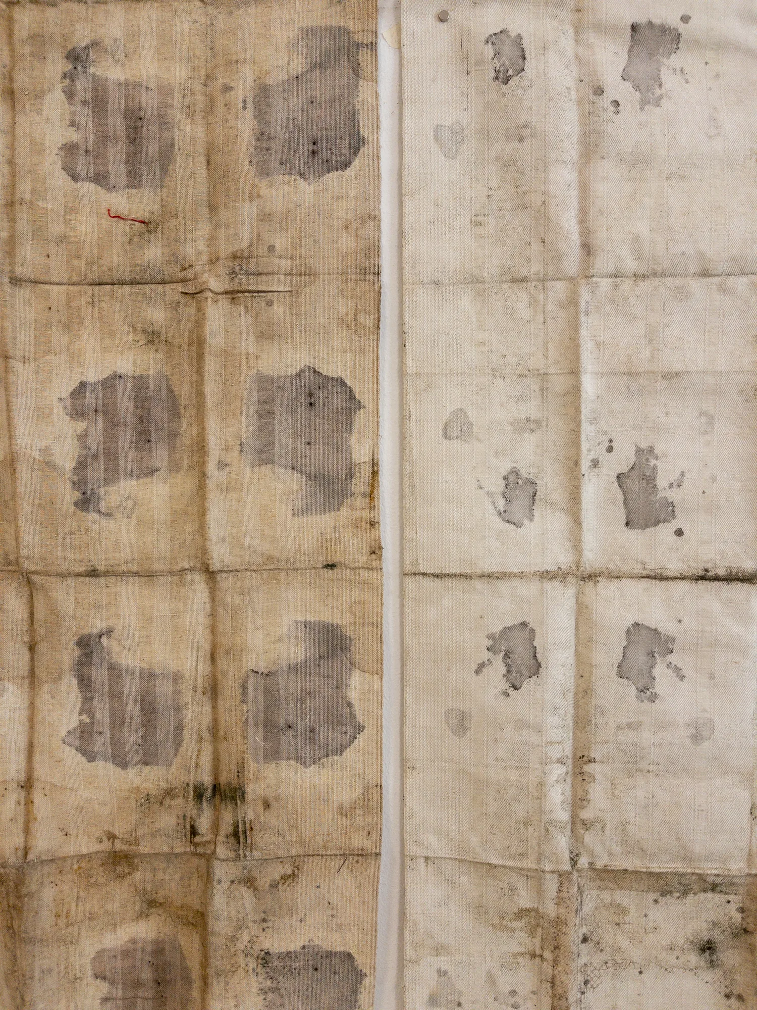 Detalle de las telas, con una cuadrícula de pliegues y manchas que evocan mapas
